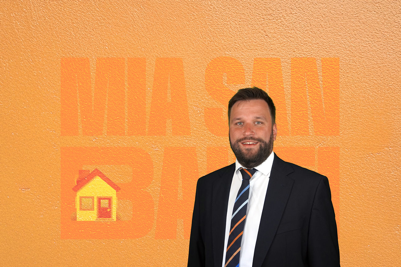 Ein Mann steht vor einem orangen Hintergrund.