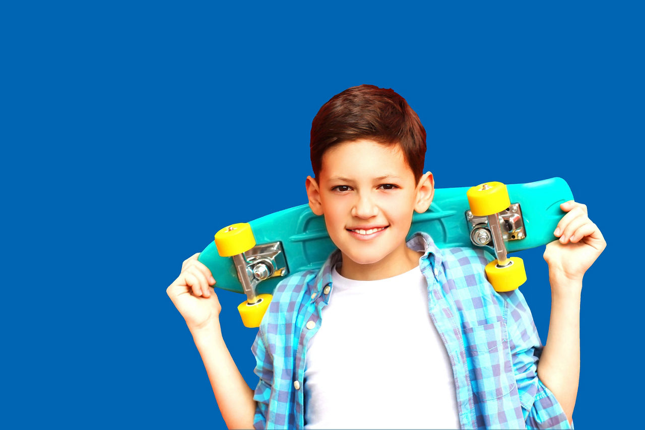 Ein Junge hebt ein Skateboard über seinen Kopf.