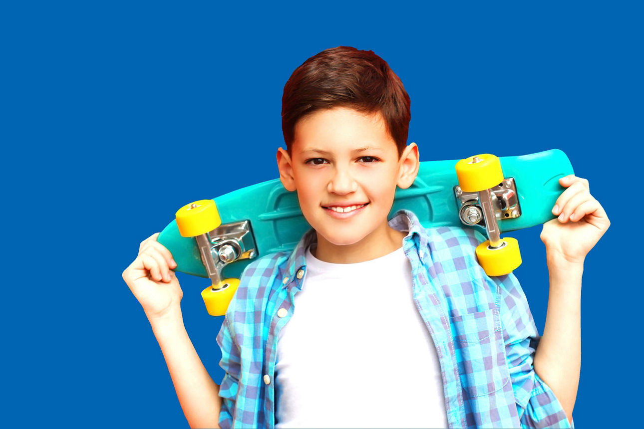 Ein Junge hebt ein Skateboard über seinen Kopf.