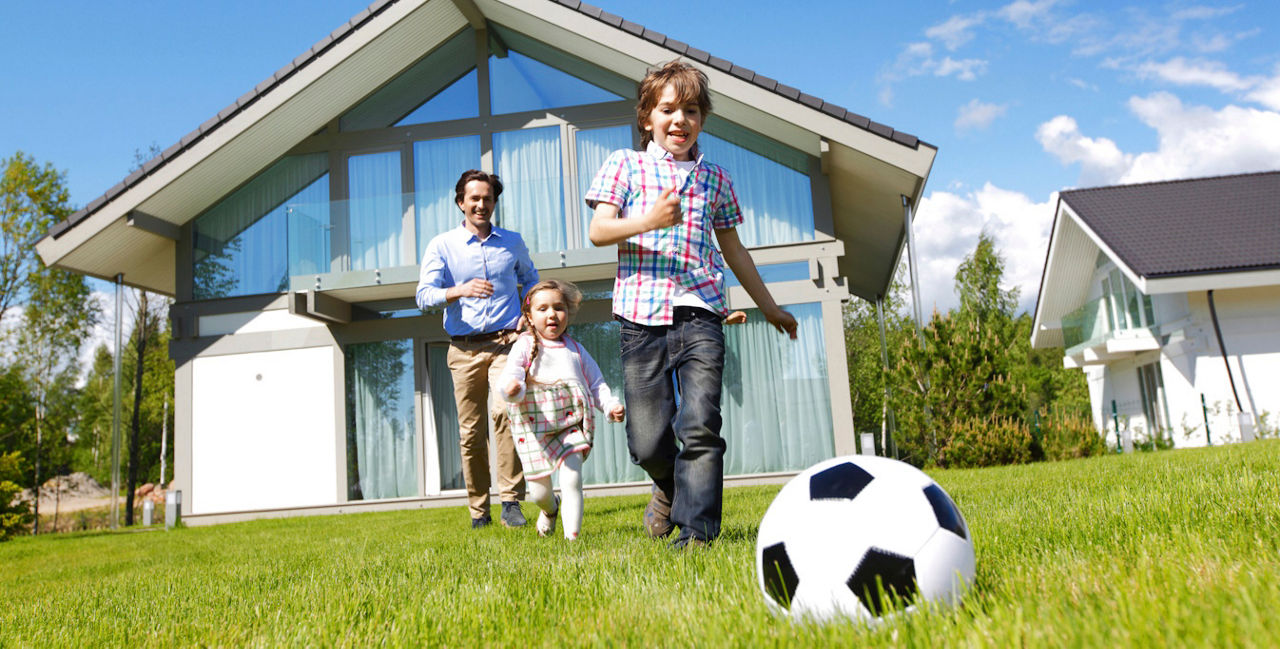Mann spielt mit Kindern im Garten Ball 