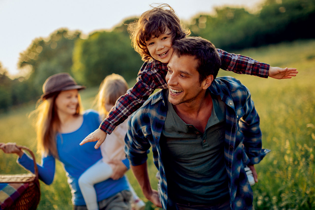 Familie mit zwei Kinder läuft lachend auf einer Wiese