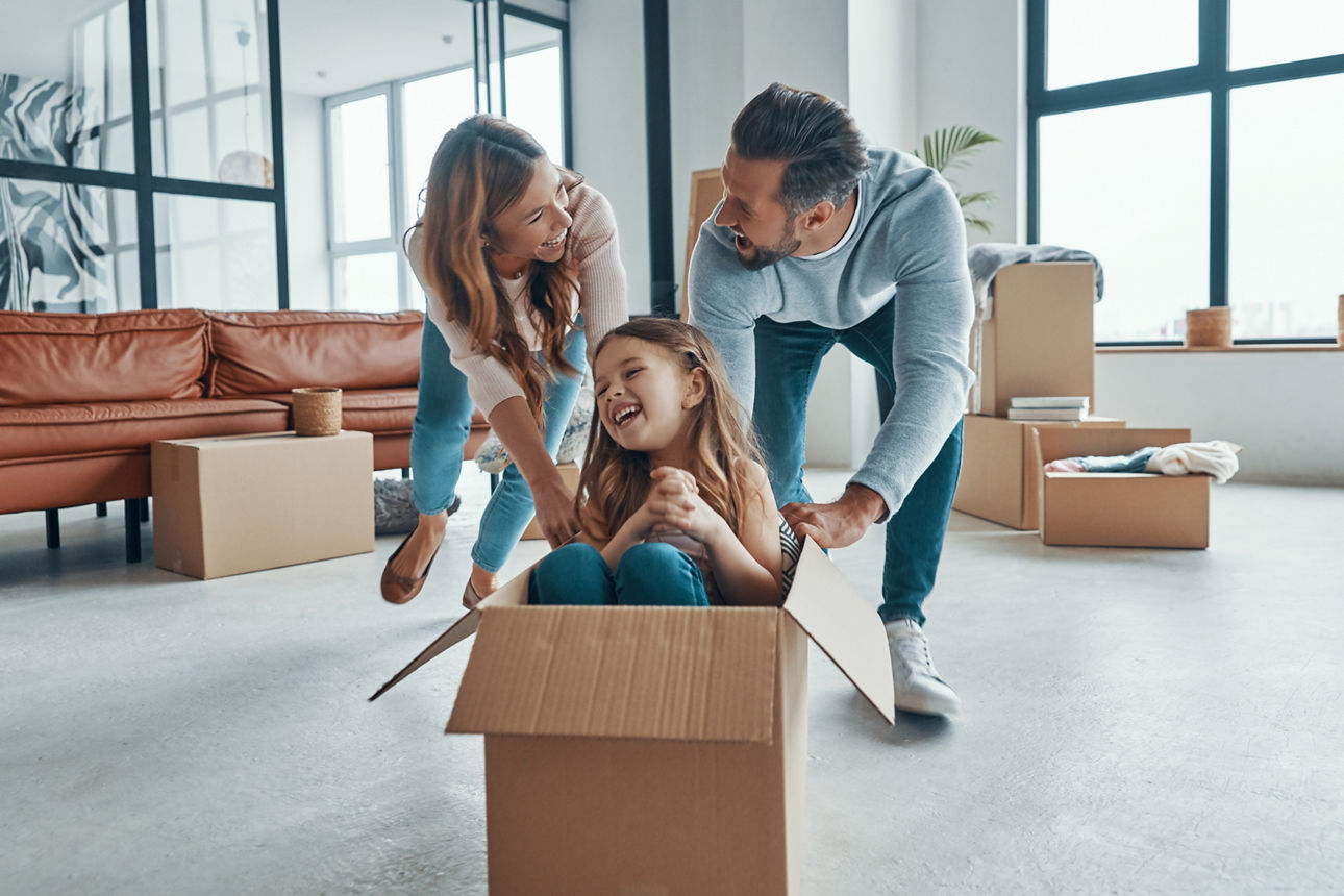 Playful young family smiling and unboxing their stuff while moving into a new apartment