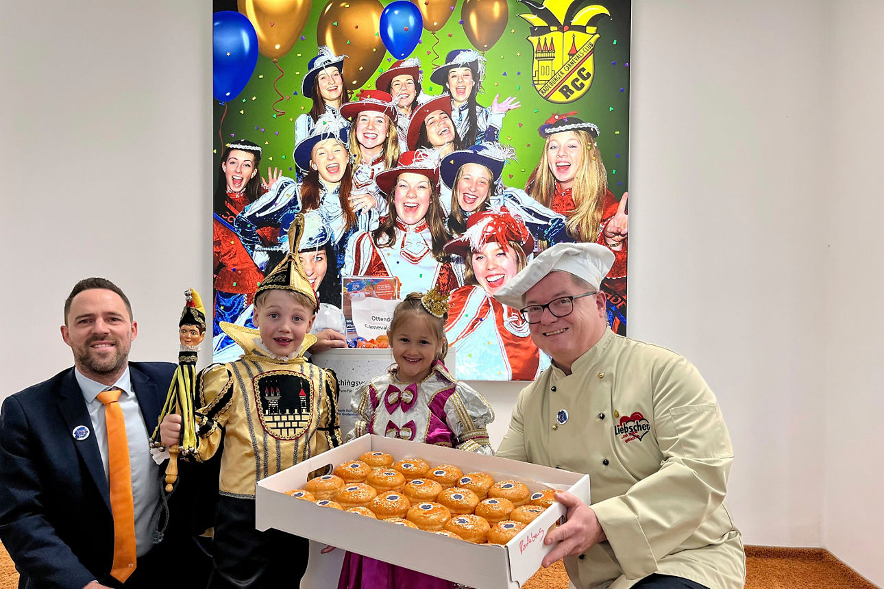 Zwei Kinder und zwei erwachsene Männer in Faschingsköstumen halten lächend eine Schachtel Berliner.