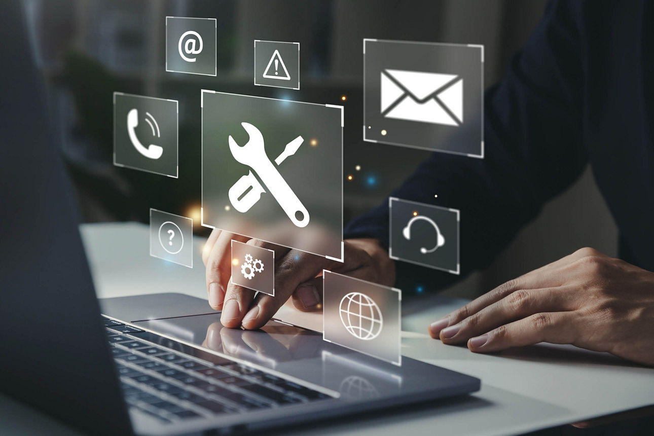 Händer am Laptop und Symbole für Schraubschlüssel und Briefumschlag schweben in der Luft 