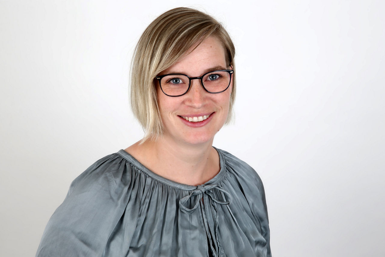 Eine lächelnde Frau schaut in die Kamera.