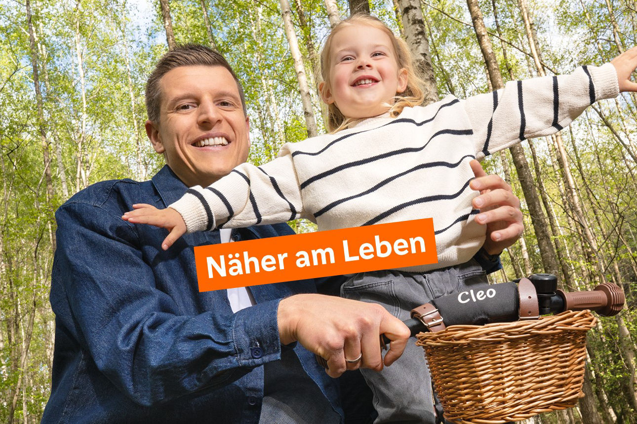 Vater der seine Tochter auf einem Fahrrad festhält