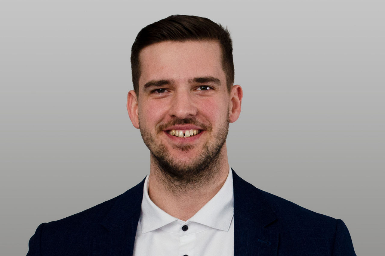 Privatkundenberater Niklas Fellenberg vor grauen Hintergrund