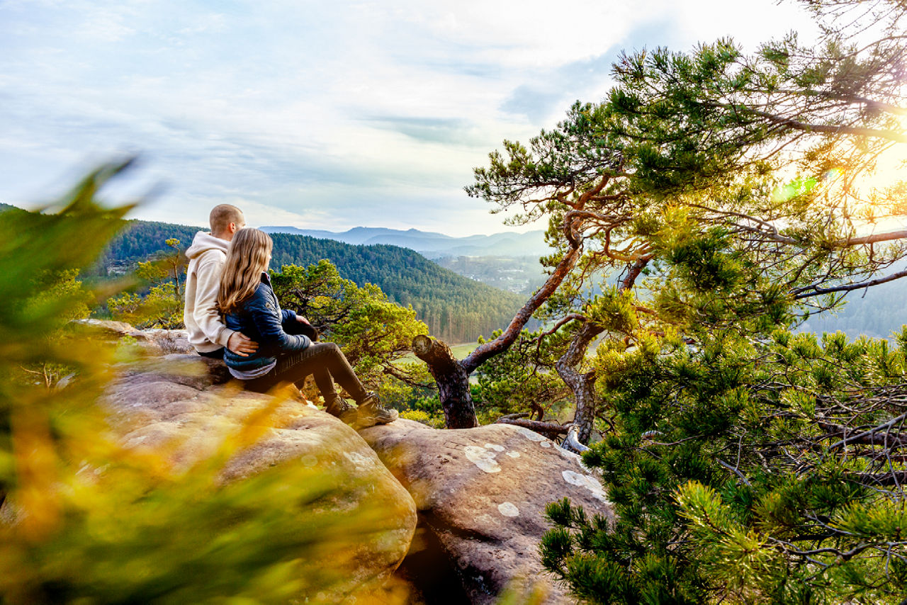 Ein Pärchen auf einem Fels sitzend in die Weite schauen