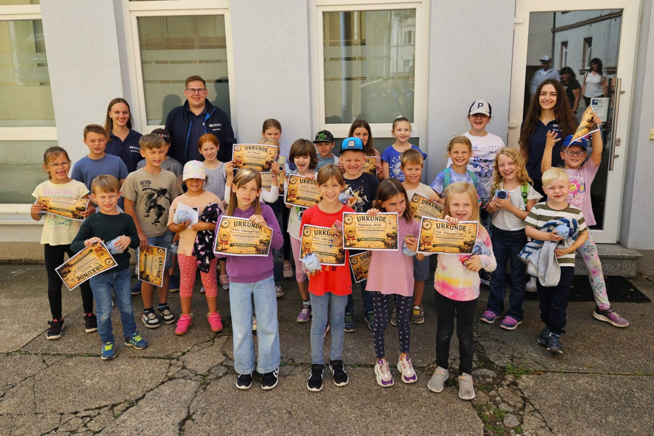 Eine Gruppe von Kindern hält ihre Schatzsucher-Urkunden in die Kamera