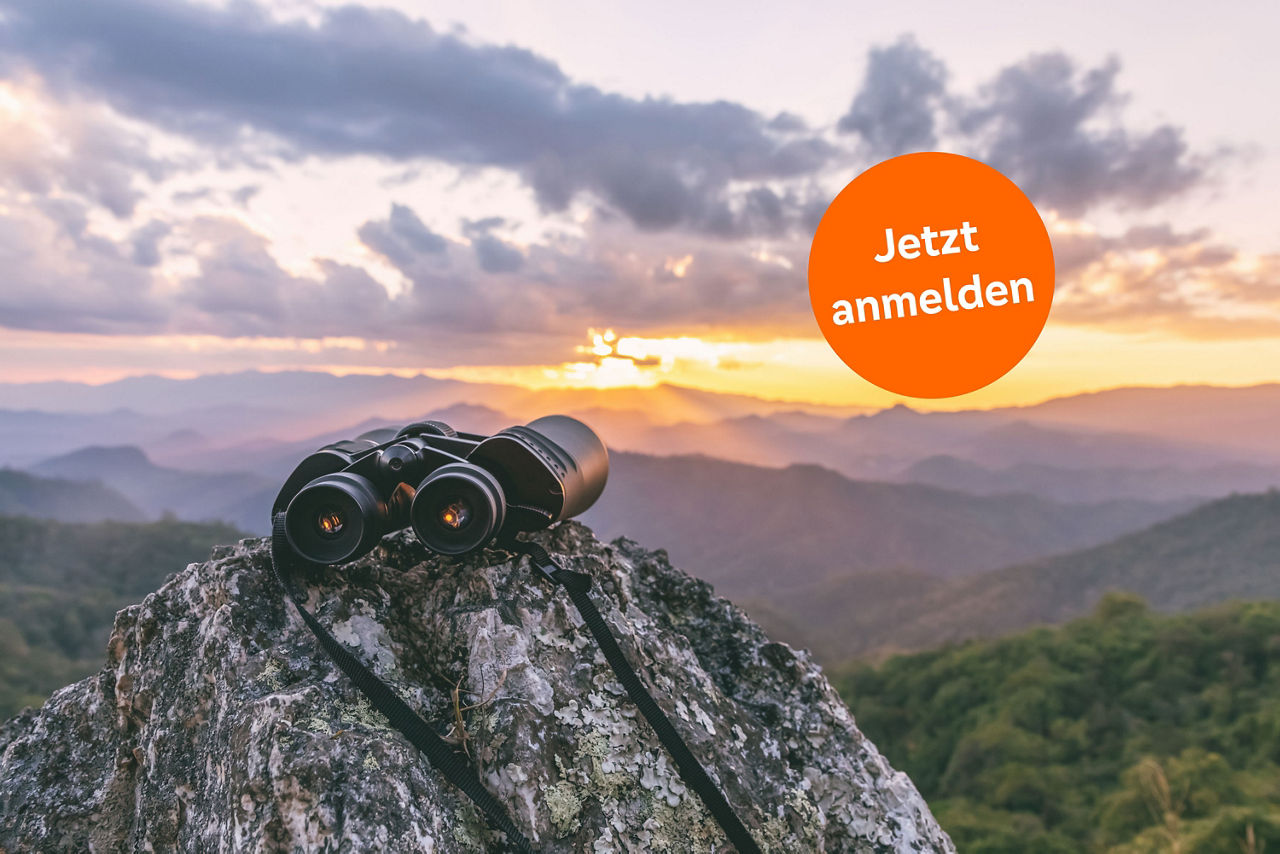 Fernglas auf einem Felsen bei Sonnenuntergang mit Text: Jetzt anmelden