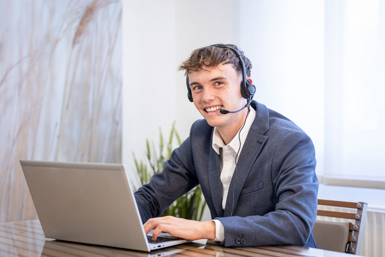 Junger Mann lächelt freundlich und trägt ein Headset