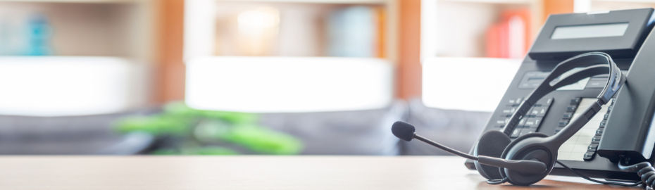 Ein Schreibtisch in einem Konferenzraum mit einem Telefon und einem Headset für eine Besprechung.