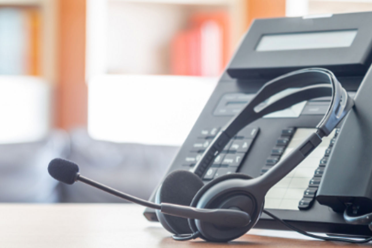 Ein Schreibtisch in einem Konferenzraum mit einem Telefon und einem Headset für eine Besprechung.