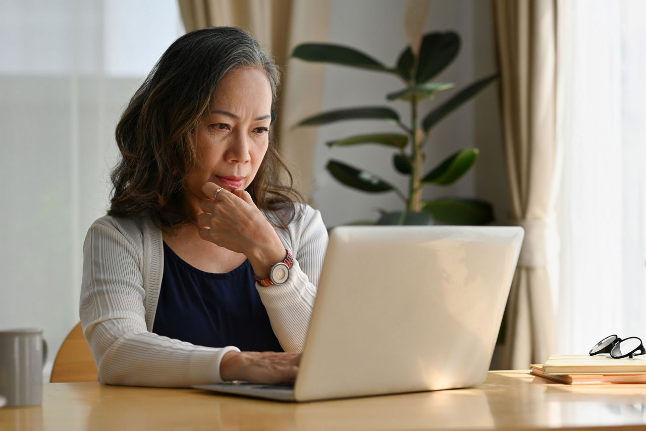 Alte Frau arbeitet zu Hause mit Notebook