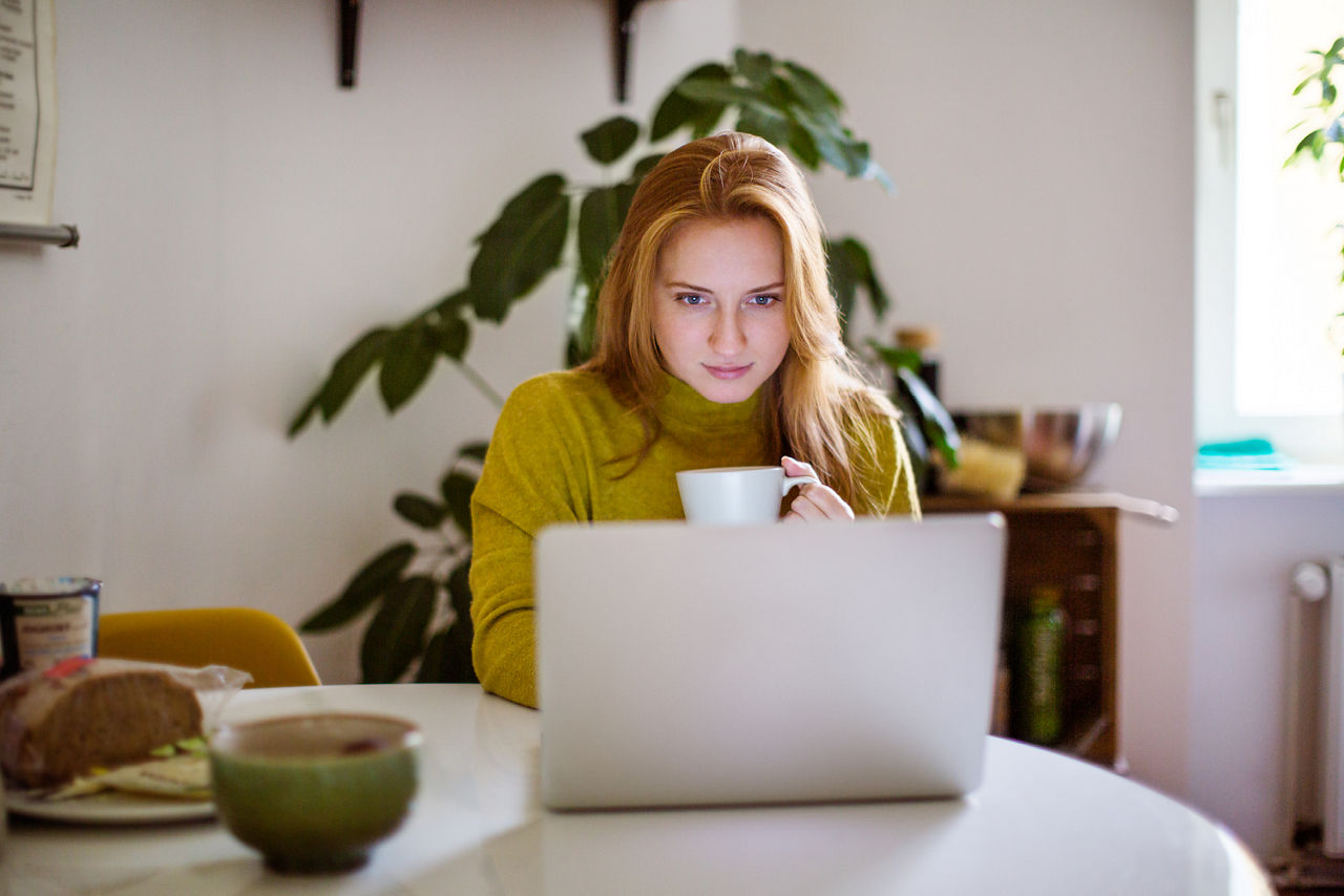 Frau mit Tasse sitzt vor Laptop