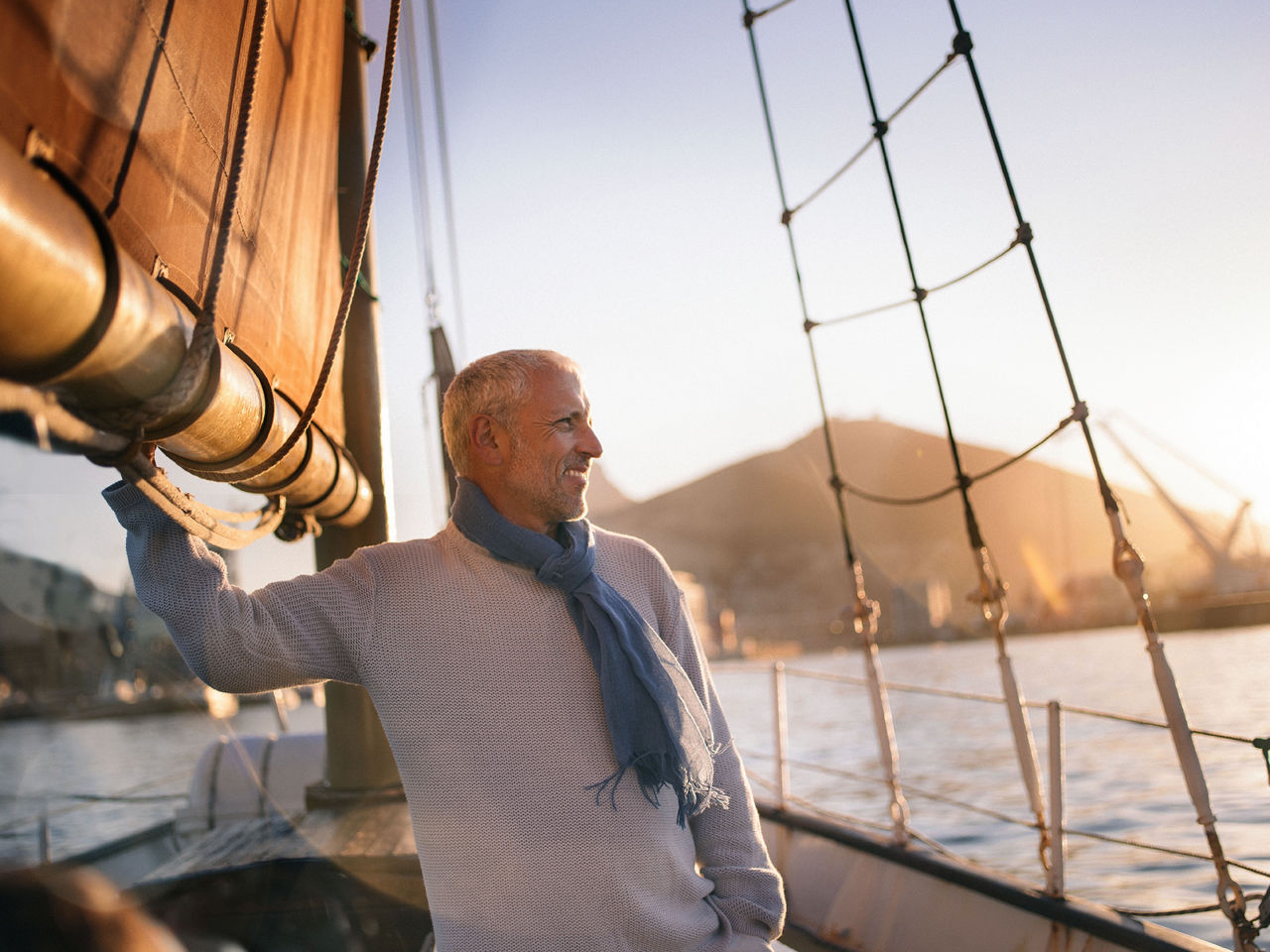 Mann steht auf einem Segelboot im Sonnenuntergang