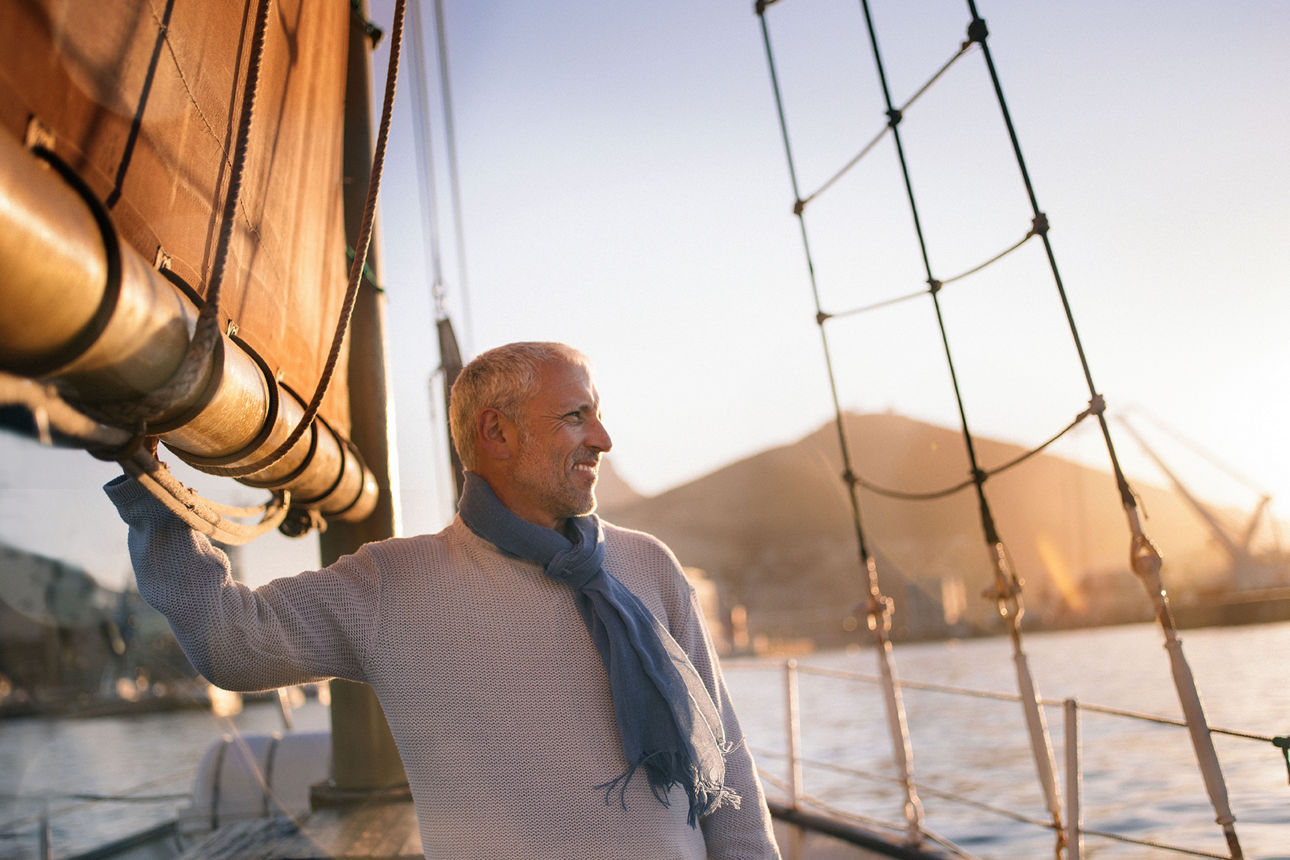 Mann steht auf einem Segelboot im Sonnenuntergang