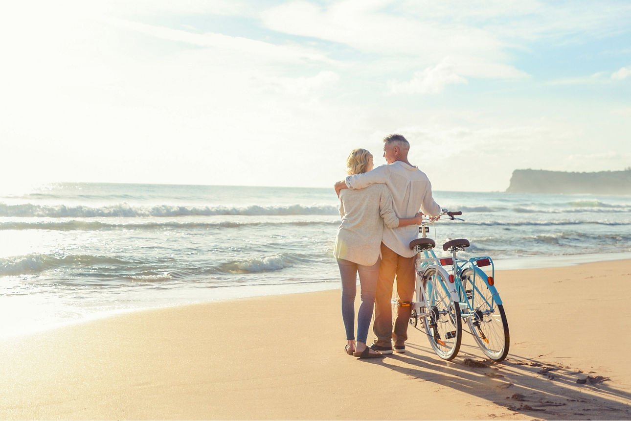Zwei Personen sind mit Fahrrädern am Strand