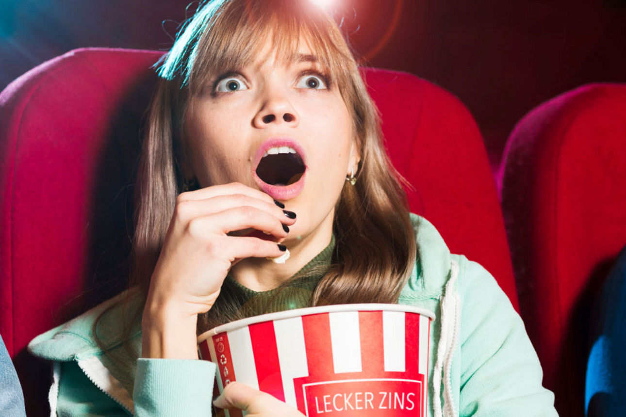 Frau sitzt im Kino und schaut gespannt einen Film
