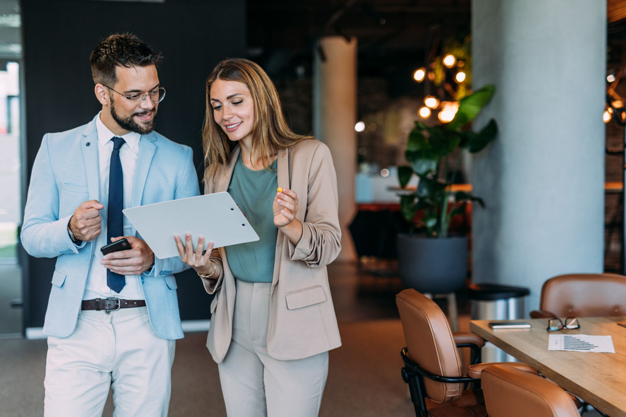 Mann und Frau in Businesskleidung schauen auf ein Board