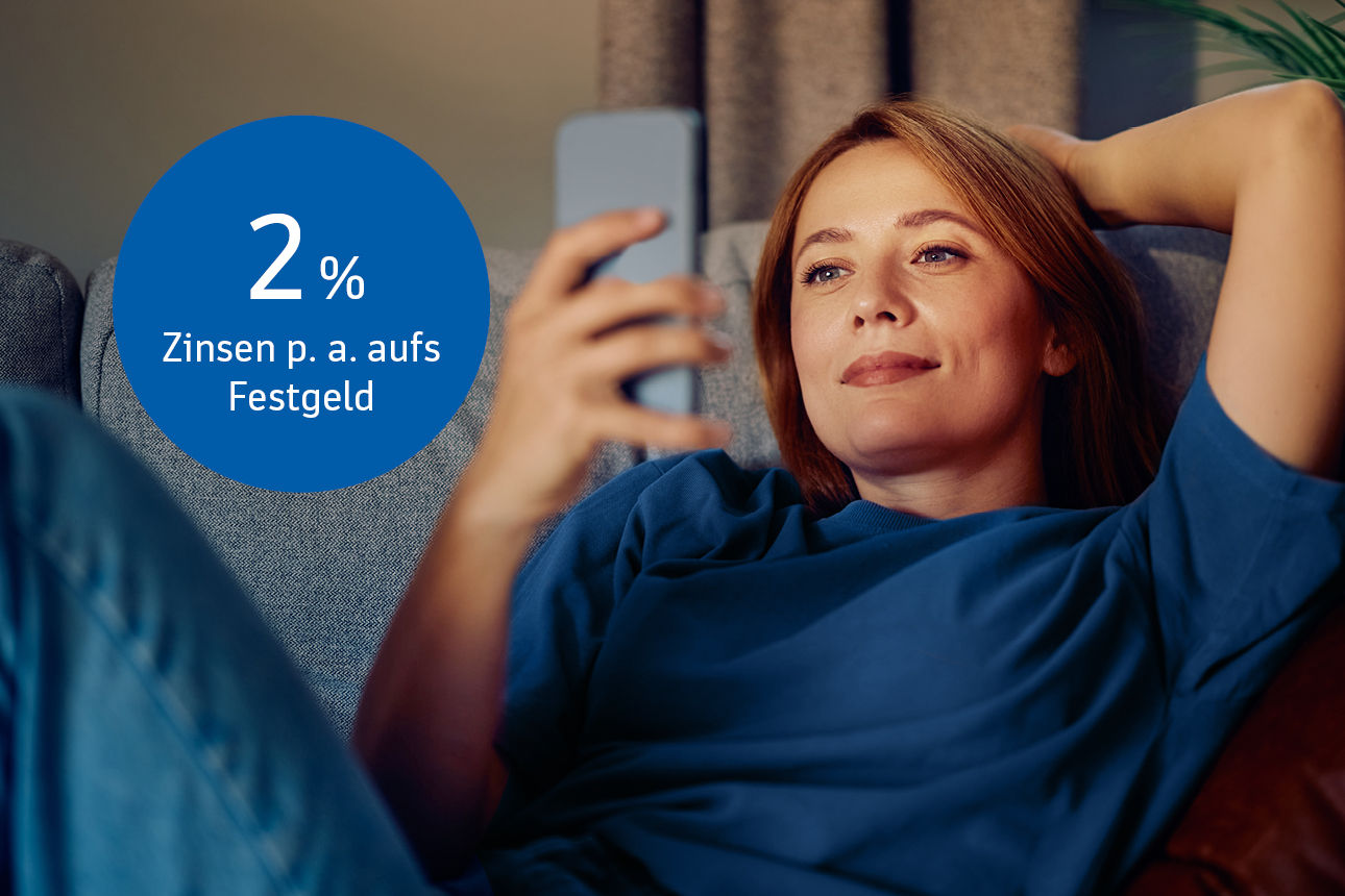 Frau liegt auf dem Sofa mit dem Handy in der Hand. Bildaufschrift: 2 % Zinsen p. a. aufs Festgeld.