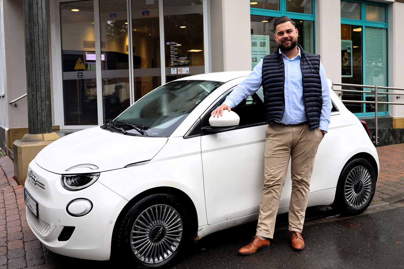 Volksbank-Kundenberater vor  einem Fiat 500 Elektroauto