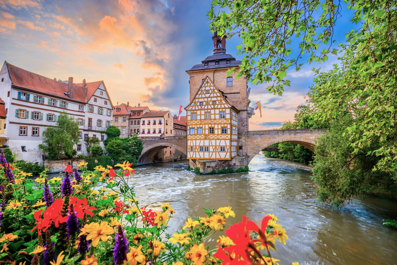 Altes Rathaus in Bamberg mit Fluss Rednitz und Blumen im Vordergrund