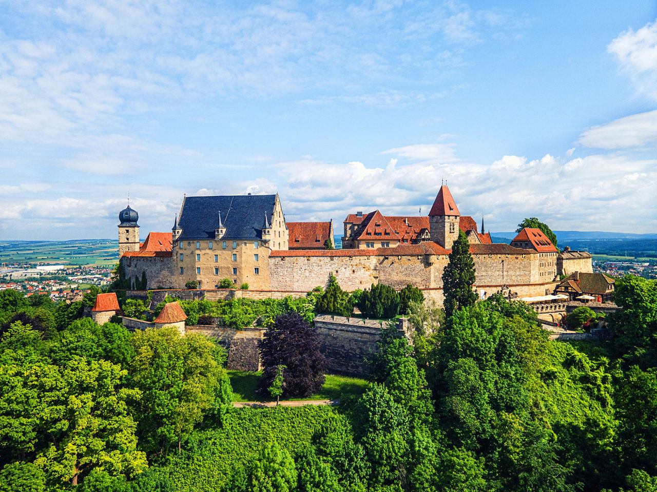 Blick auf die Veste in Coburg mit grünem Wald im Vordergrund