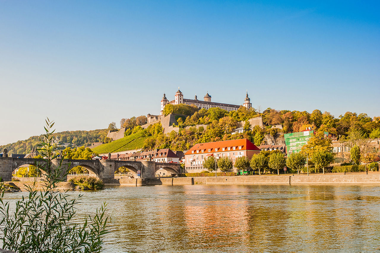Blick auf die Festung Marienberg in Würzburg mit der alten Mainbrücke und dem Fluss Main im Vordergrund
