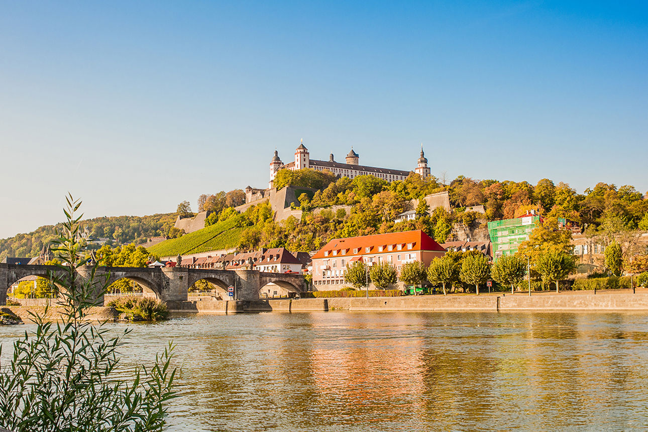 Blick auf die Festung Marienberg in Würzburg mit der alten Mainbrücke und dem Fluss Main im Vordergrund