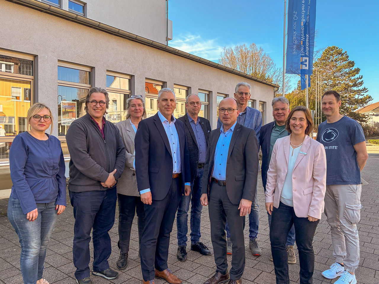 Gruppe von neun Personen vor Gebäude im Freien, gemeinsames Foto bei Termin