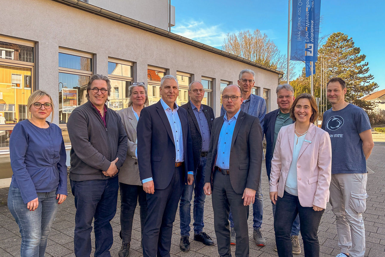 Gruppe von neun Personen vor Gebäude im Freien, gemeinsames Foto bei Termin