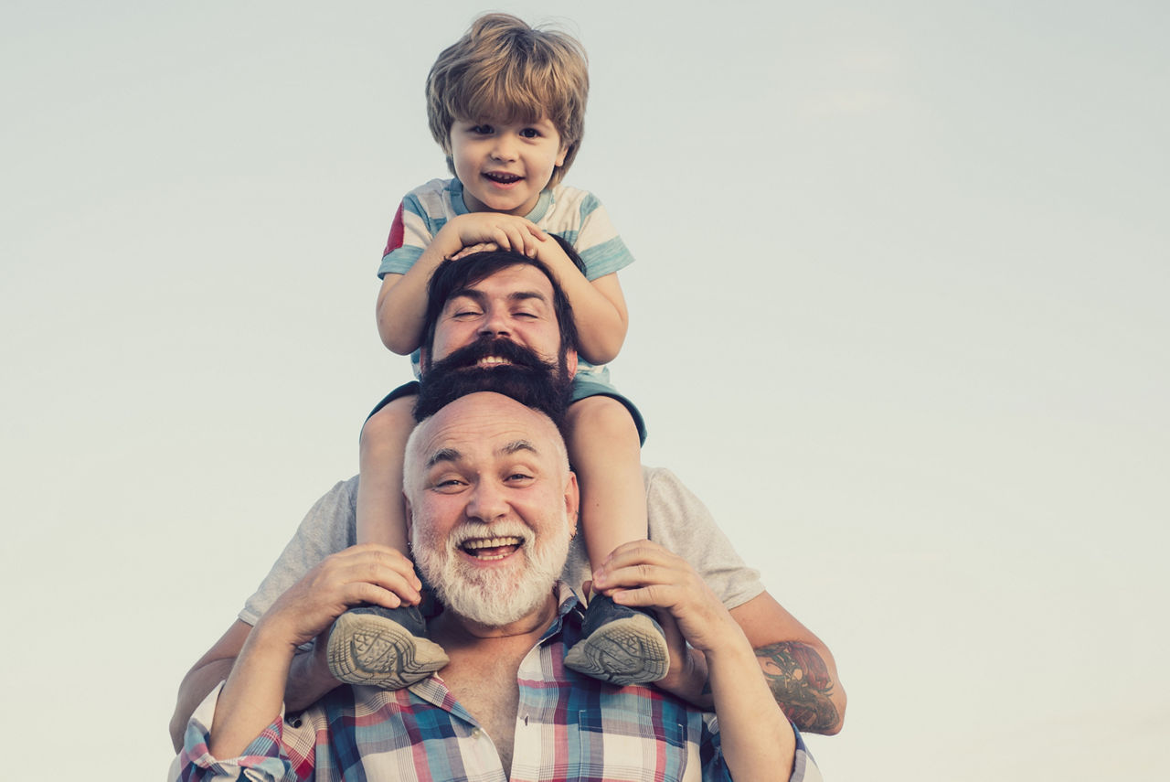 Großvater mit seinem Sohn und Enkel schauen glücklich nach vorne 