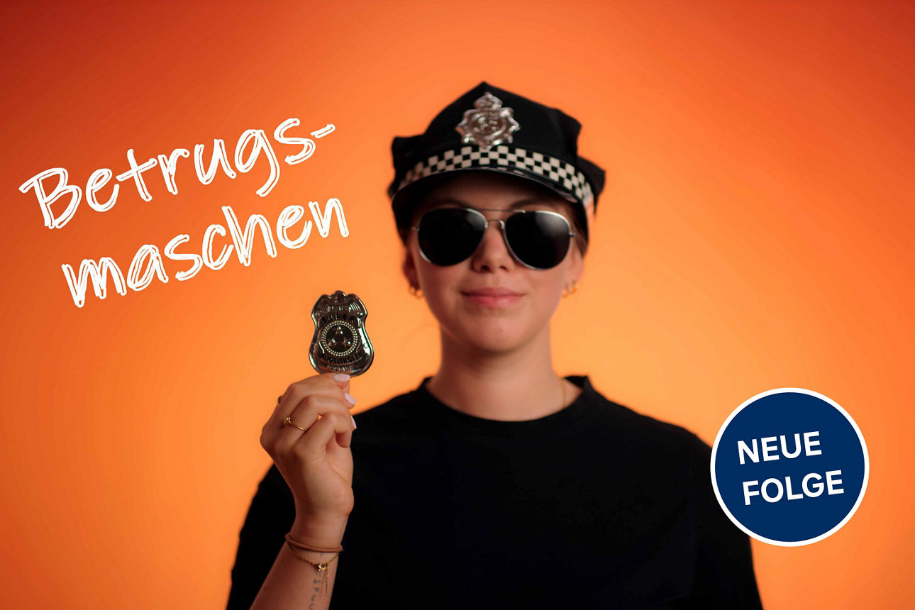 Frau mit Polizeimütze hält Polizeiabzeichen in der Hand