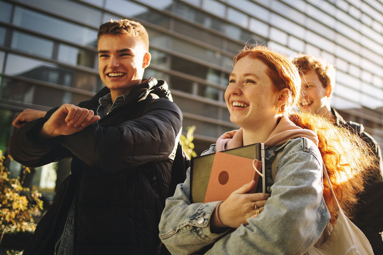 Glückliche Studenten, die zusammen draußen auf dem College-Campus spazieren gehen