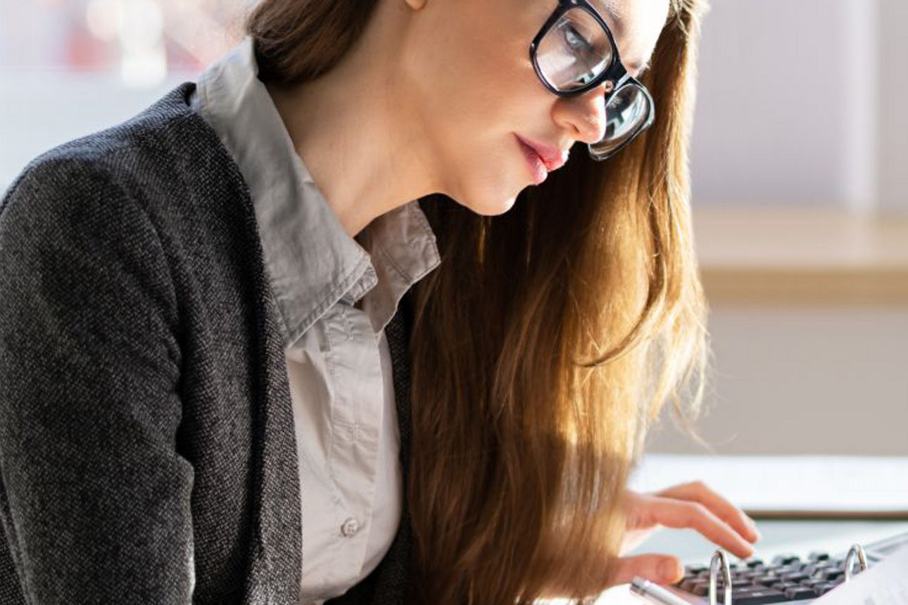 Frau arbeitet mit Dokumenten und einem Laptop