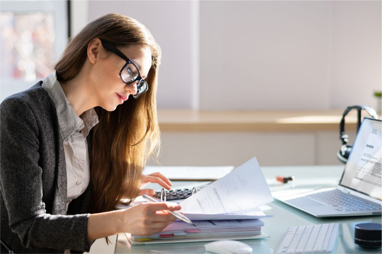 Frau arbeitet mit Dokumenten und einem Laptop