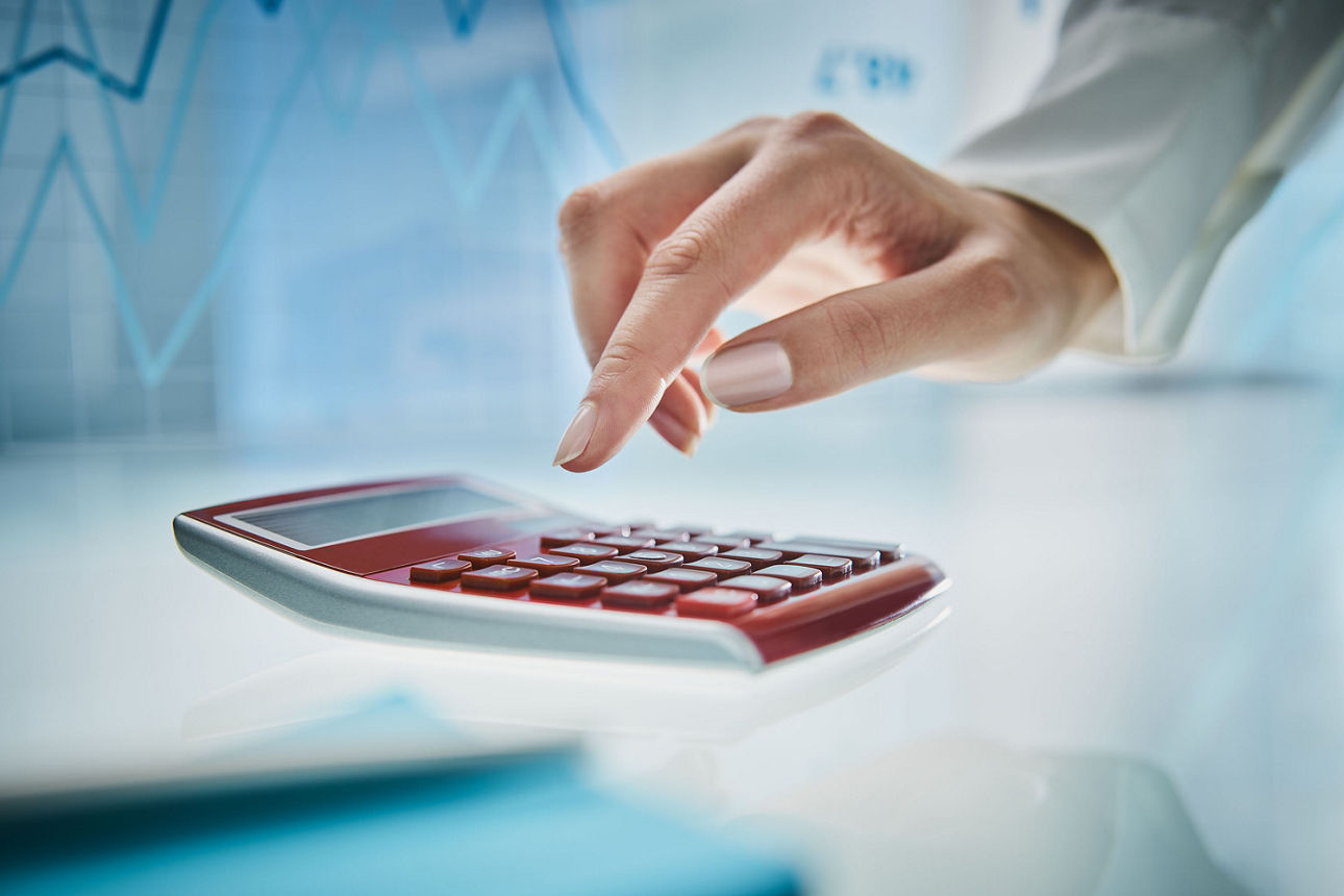 Eine Hand schwebt über einem Taschenrechner.
