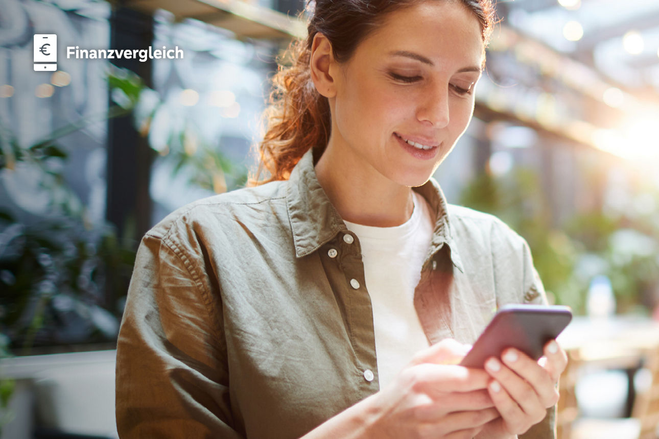 Junge Damen sitzt im Café, schaut auf Ihrem Handy den Finanzvergleich an
