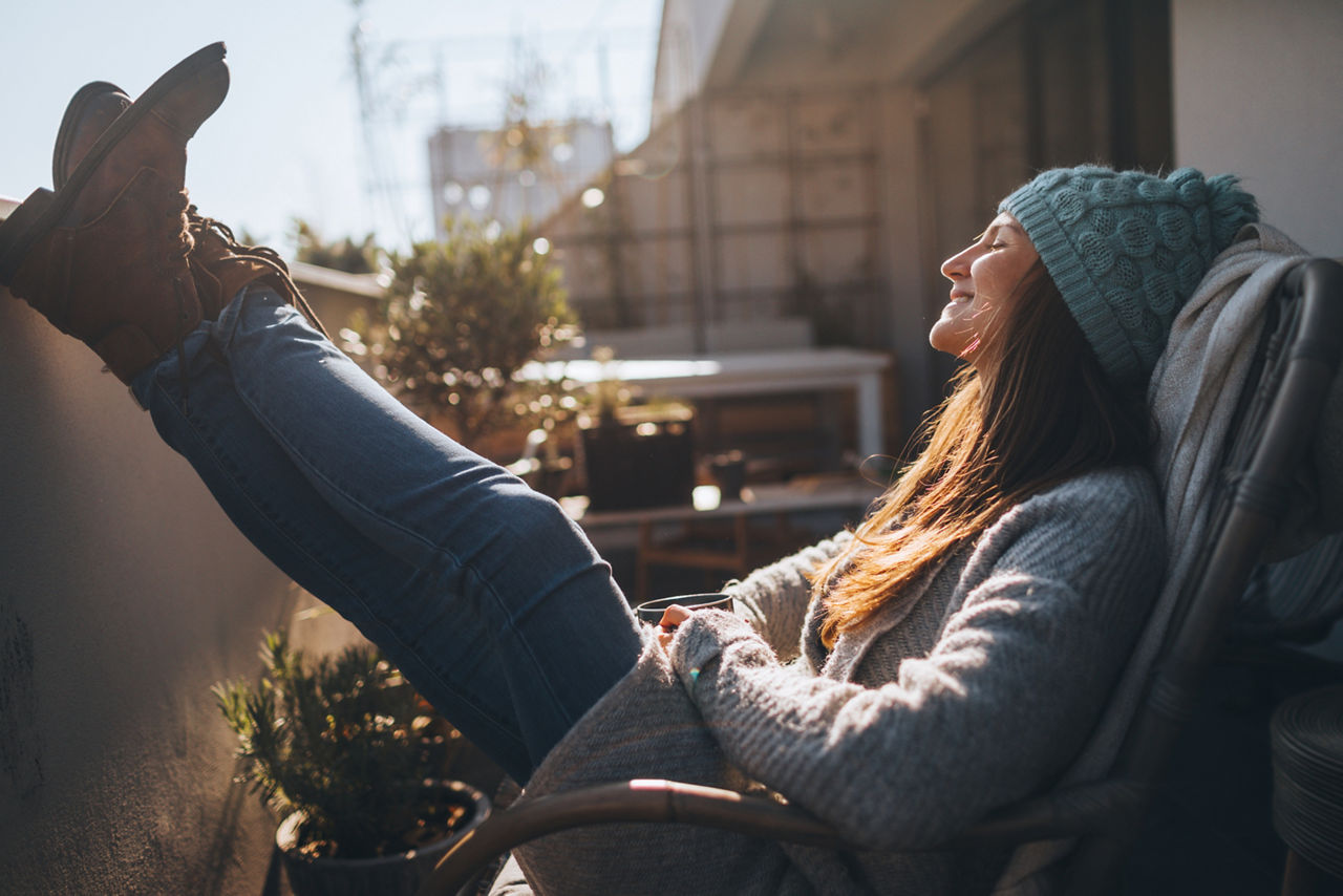 Junge Frau liegt an einem sonnigen Herbsttag auf ihrem Balkon