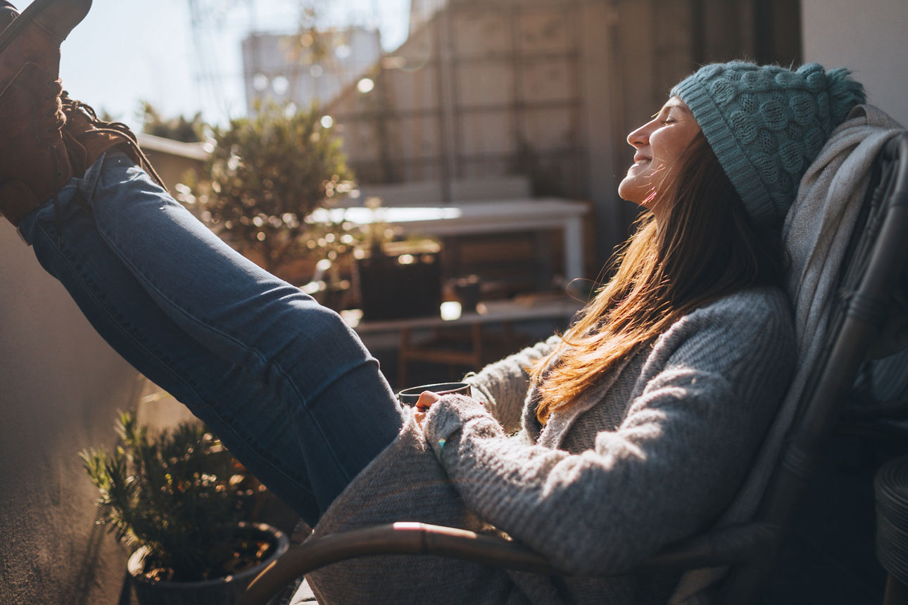 Junge Frau liegt an einem sonnigen Herbsttag auf ihrem Balkon