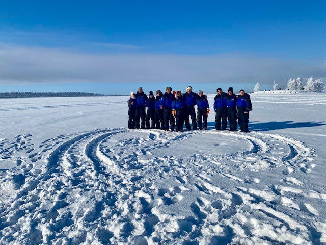 Reisegruppe steht auf dem gefrorenen finnischen Meerbusen mit einem großen Herzen davor im Schnee