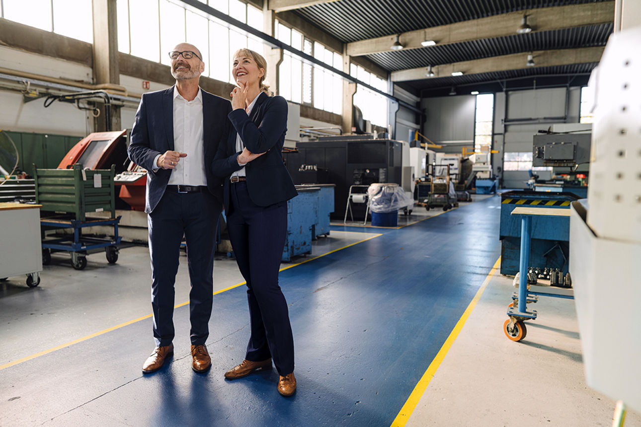 Mann und Frau in einer Fertigungshalle