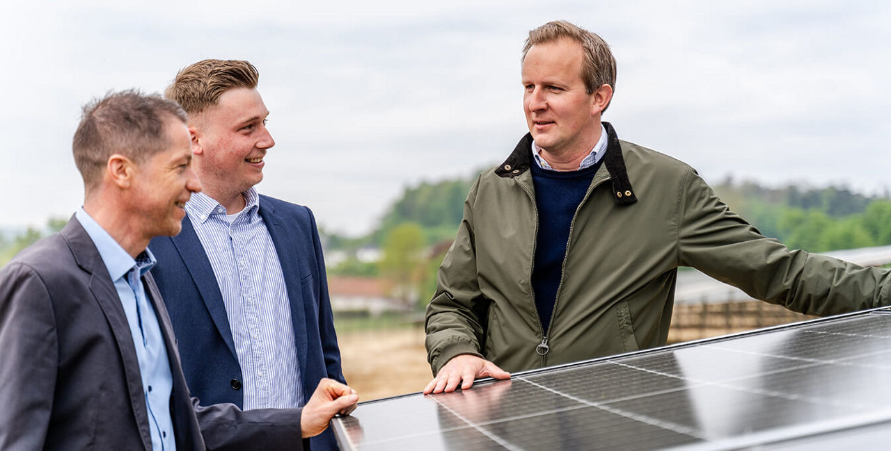 Drei Herren, die um eine Photovoltaikanlage stehen