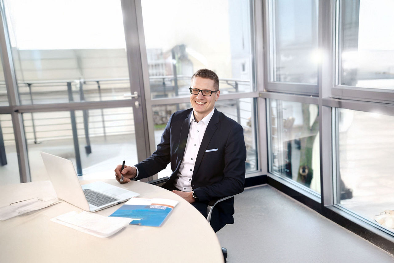 Firmenkundenberater Martin Haubner sitzt mit Unterlagen und Laptop an einem Besprechungstisch