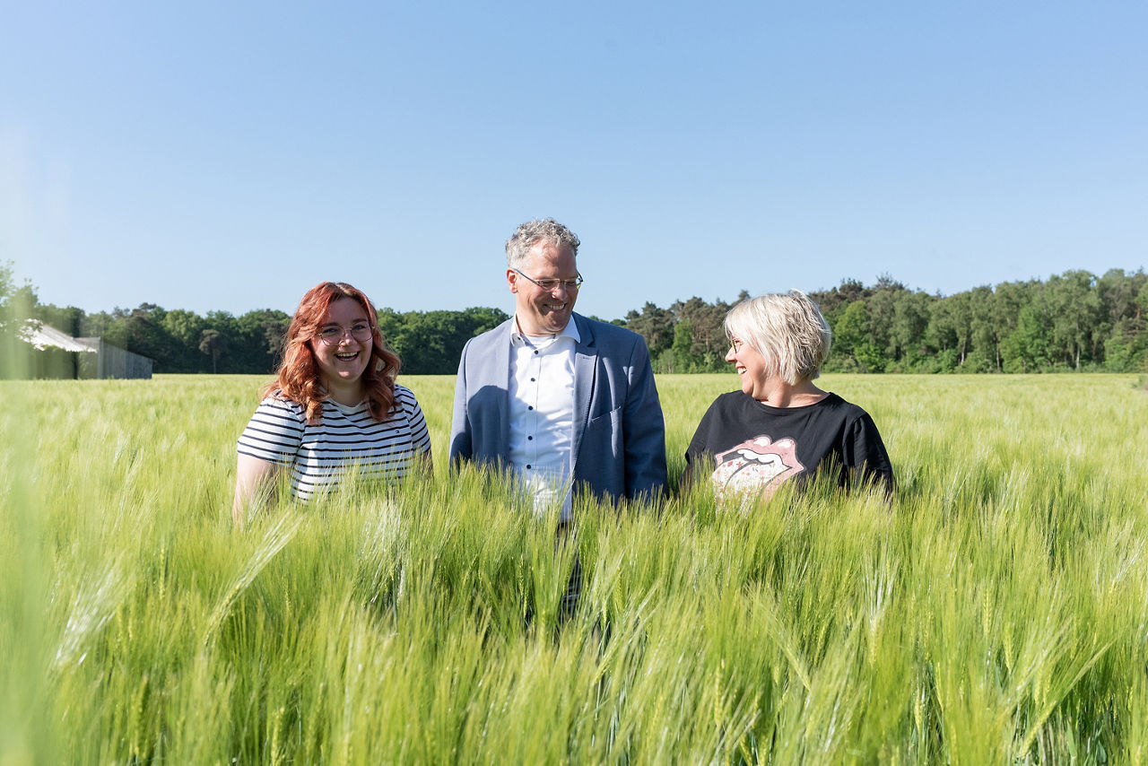 Unsere Firmenkundinnen Jonna und  Silke Sümpelmann mit Heribert Triptrap (Kundenberater) in ihrer Mitte auf einem Weizenfeld