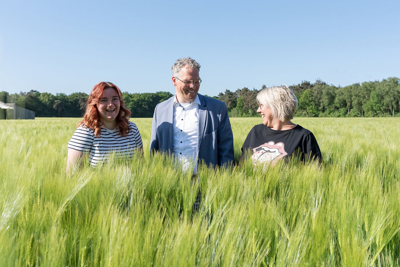 Unsere Firmenkundinnen Jonna und  Silke Sümpelmann mit Heribert Triptrap (Kundenberater) in ihrer Mitte auf einem Weizenfeld