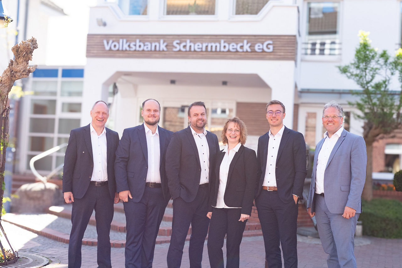 Fünf Männer und eine Frau stehen vor dem Haupteingang der Volksbank Schermbeck