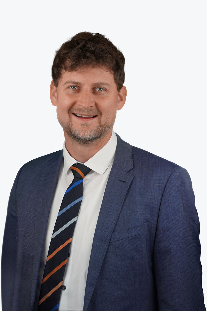 Ein Mann mit Krawatte, aus dem Unternehmen VR Bank Mittlere Oberpfalz, schaut lächeld in die Kamera.