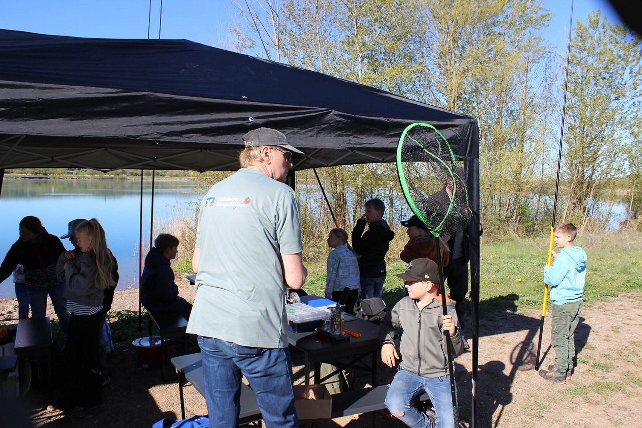 Gruppe Jugendlicher mit Betreuer mit einem Pavillion am See